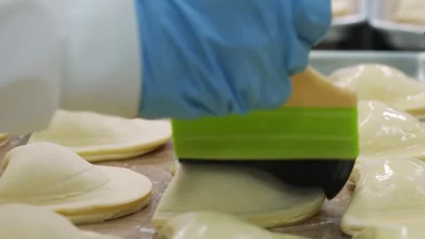 Professional pastry chef in blue gloves using a green dough scraper to cut and s Stock Footage 337751403