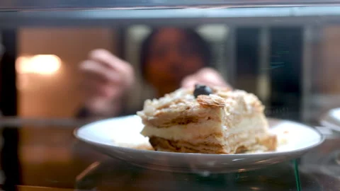 Professional pastry chef lifting delicate mille feuille from chilled display Stock Footage 312022894