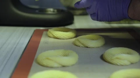 Professional pastry chef piping choux dough for Paris-Brest on silicone mat Stock Footage 327736137
