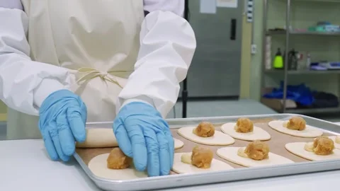 Professional pastry chef in uniform and blue gloves assembling fruit-filled hand Stock Footage 337751384
