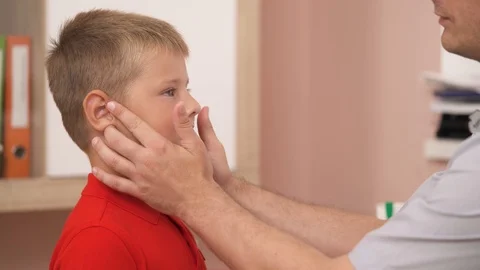 Professional pediatrician checking swollen lymph nodes of his patient. Stock Footage 114074593