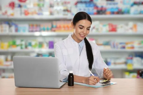 Professional pharmacist working at table in modern drugstore Stock Photos