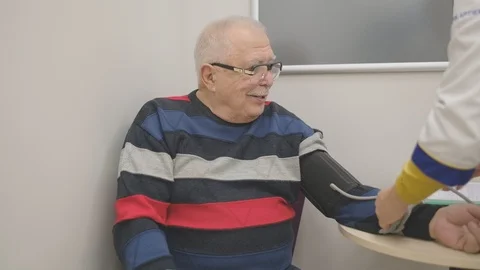 Professional pharmacy worker checks old man blood pressure Stock Footage 125581554