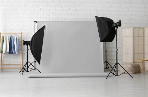 Professional photo studio setup with gray backdrop, softboxes, and clothing r Stock Photos