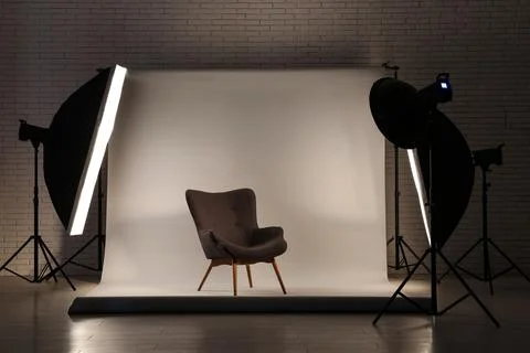 Professional photography studio setup with softbox lighting and empty armchai 库存照片