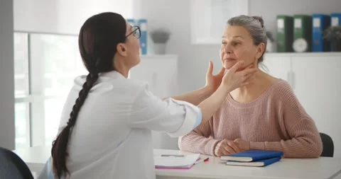 Professional physician checking neck lymph nodes of old woman Stock Footage 152890374