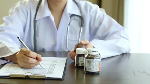 Professional physician gp wearing white coat writing notes using a pen at Stock Footage 336587571