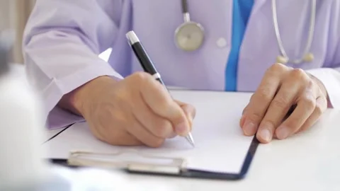 Professional physician gp wearing white coat writing notes using a pen at Vídeo Stock 336587577