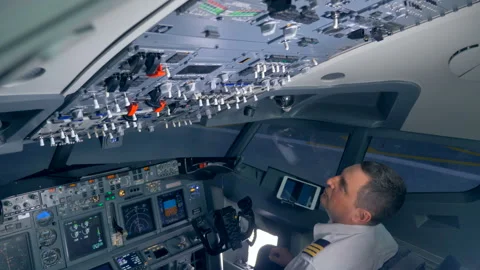 Professional pilot is regulating various switches on a airplane cockpit deck. Stock Footage 93662315