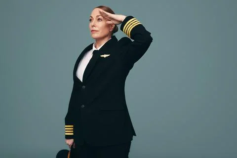 Professional pilot saluting while standing in a studio Stock Photos