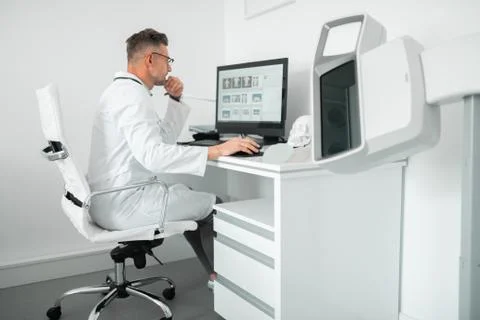 Professional plastic surgeon sitting at the computer while working Stock Photos
