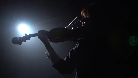 Professional playing the violin in a dark studio with a lantern from it glare Video stock 99442357