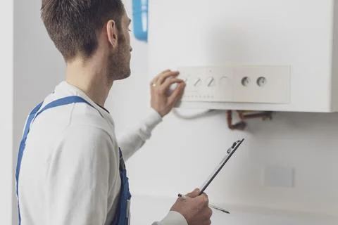 Professional plumber checking a boiler control panel Stock Photos
