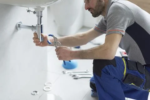 Professional plumber checking a sink drain Stock Photos