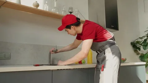 Professional Plumber Inspecting Kitchen Sink Pipes During Daytime Maintenance Stock-Footage 274552297