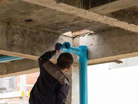 Professional plumber installing and aligning blue PVC drainage pipe elbows .. Stock Photos