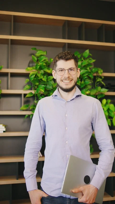 This is a professional portrait of a smiling young man in a modern office Stock Footage 285682525