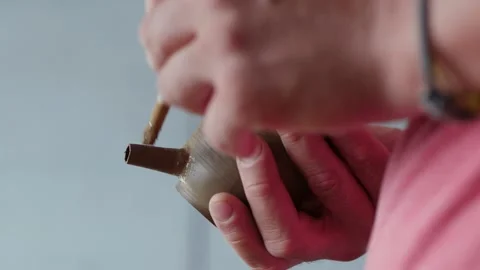 A professional potter brushes with water a clay spout on a clay teapot. Craft Stock Footage 145543953