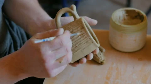 Professional potter making pattern on clay mug with special tool in workshop Stock Footage 105750438