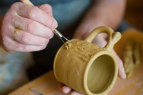 Professional potter making pattern on clay mug with special tool in pottery Stock Photos