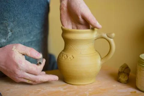 Professional potter making pattern on clay jar with special tool in pottery Stock Photos