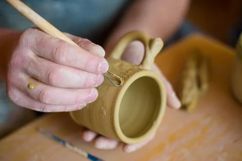 Professional potter making pattern on clay mug with special tool in pottery Stock Photos