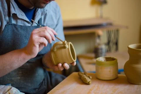 Professional potter making pattern on clay mug with special tool in pottery Stock Photos