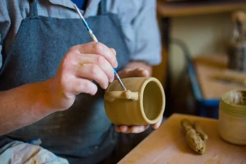 Professional potter making pattern on clay mug with special tool in pottery Stock Photos