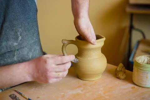 Professional potter making pattern on clay jar with special tool in pottery Stock Photos