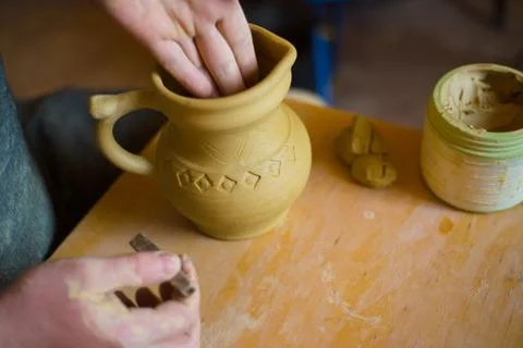 Professional potter making pattern on clay jar with special tool in pottery Stock Photos