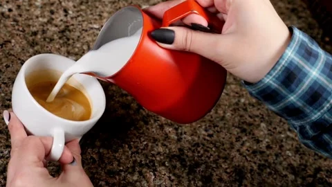 Professional pouring stream milk to create a latte art pattern in white cup. 動画素材 334649979