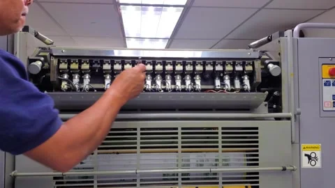 Professional printer adjusting mechanical components of an industrial offset Stock Footage 338027824