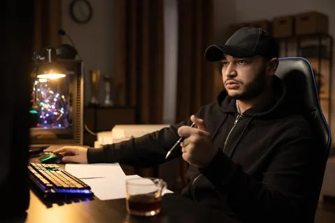 A professional programmer sits late at night at a computer with a light on 写真素材