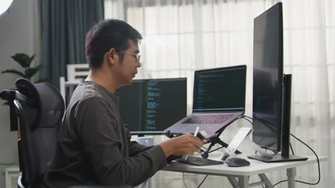 Professional Programmer Working on Multiple Screens in a Home Office Setup Stock-Footage 336680414