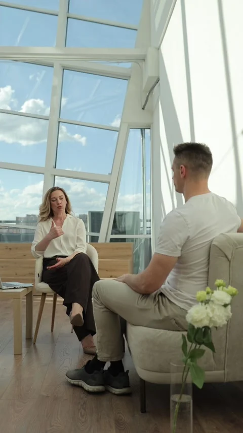 A professional psychologist is consulting a young client while sitting in a Stock Footage 323915122