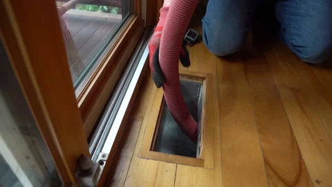 Professional pushing vacuum hose through a floor air conditioning duct Stock Footage 195457472