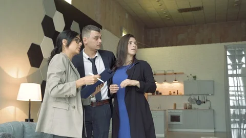 Professional real estate agent presenting young couple a house or apartment. Stock Footage 119338540