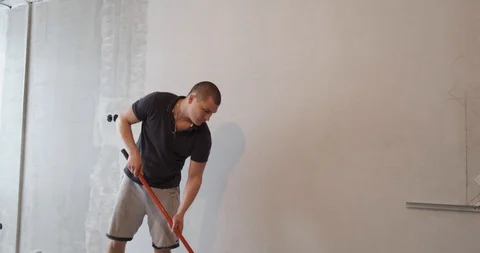 Professional repairman using roller lays primer on white wall, apartment repair Stock Footage 128972549