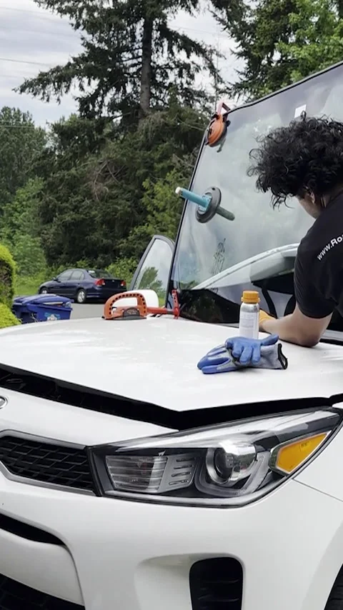 Professional replaces windshield in white car with care and precision. Stock Footage 289298752
