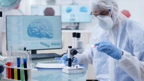 Professional researcher in protective coverall looking at a blood sample Video stock 108738873