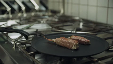 Professional restaurant chef cooking large shrimp wrapped in bacon on a skillet Stock Footage 199459948
