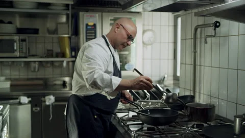 Professional restaurant chef cooking over a stove top in an industrial kitchen w Stock Footage 199462906