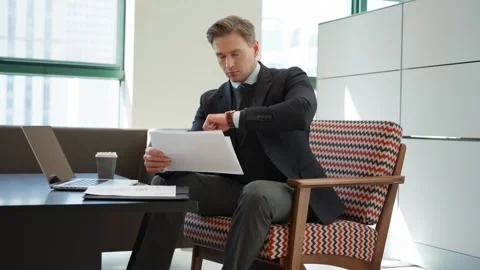 A professional reviews papers while checking time in a bright office - parallax Vídeo Stock 302185281