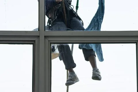 Professional rope access window cleaner working at height on building exter.. Photos