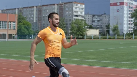 Professional Runner with Artificial Leg Jogging on Stadium Stock Footage 99767886