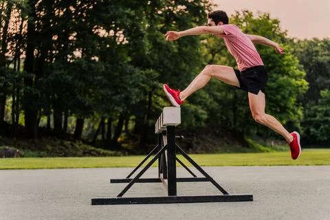 Professional runner jumping high to overcome an obstacle in a track race Stock Photos