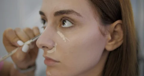 Professional salon worker smooths concealer on lady face Stock Footage 124261252
