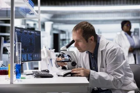 Professional science expert uses microscope as observation tool with glass tray Stock Photos