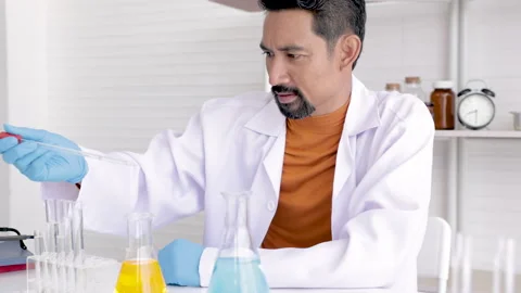 Professional scientist with beard drop liquid blue and yellow solution, tea.. Stock-Footage 243415350
