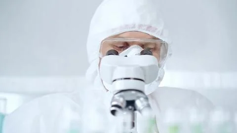Professional scientist in protective gear is using microscope in a laboratory Foto stock